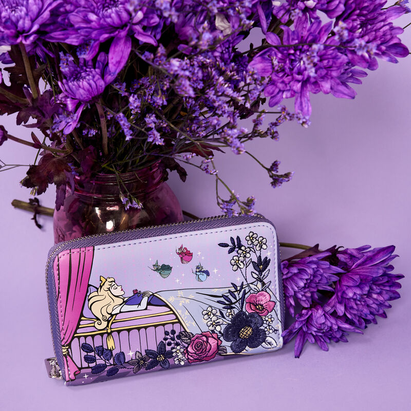 Image of the Loungefly Disney Sleeping Beauty 65th Anniversary Floral Scene Zip Around Wallet sitting under purple flowers